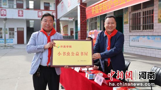 图为bet36体育在线党委副书记孙海(右1)将“小书虫”公益书屋的牌匾交到关爷庙小学校长杨少许手中。